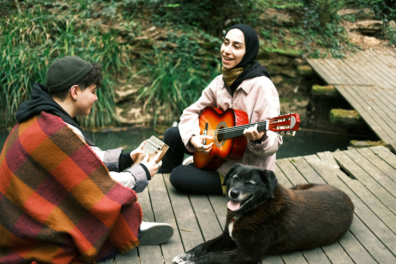 A picture of a dog that seems to be enjoying the music his human companions are playing in a dock on a lake
