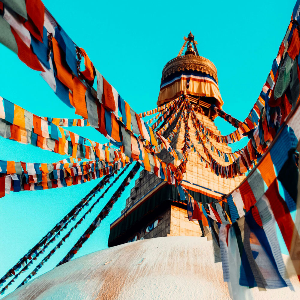 A traditional temple in nepal, with a godel top and colorful strands of fabric tied in sequence , an overall stunning image
