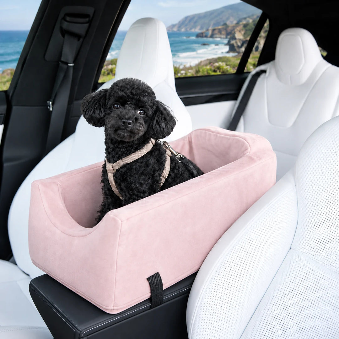 Animals Matter Companion Console Car Seat in Ice Pink inside a white luxury SUV, featuring a black toy poodle with a coastal view.