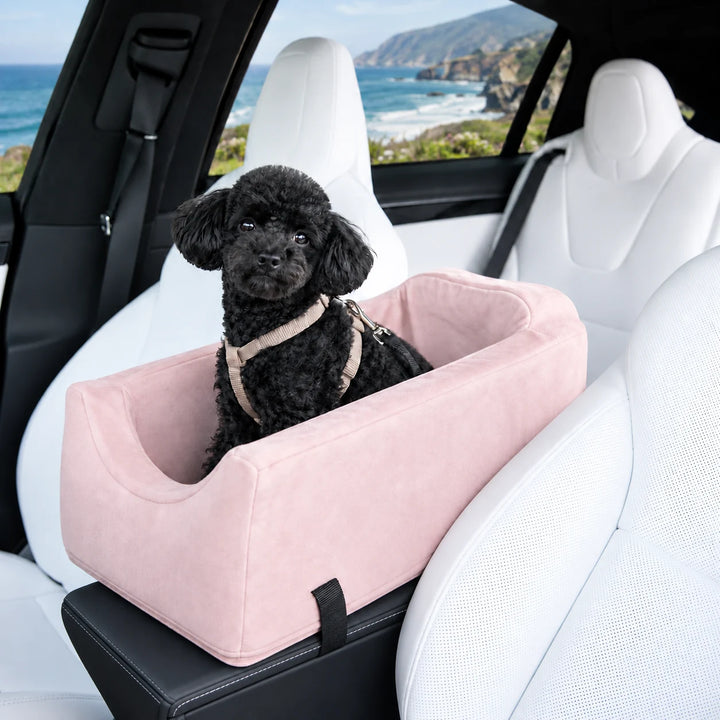 Animals Matter Companion Console Car Seat in Ice Pink inside a white luxury SUV, featuring a black toy poodle with a coastal view.