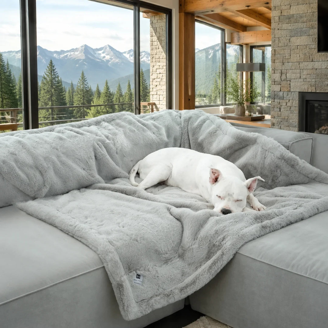 Animals Matter Ruby Puff® Waterproof Luxury Dog Blanket in light gray, with a white dog asleep on plush faux fur in a modern mountain home.